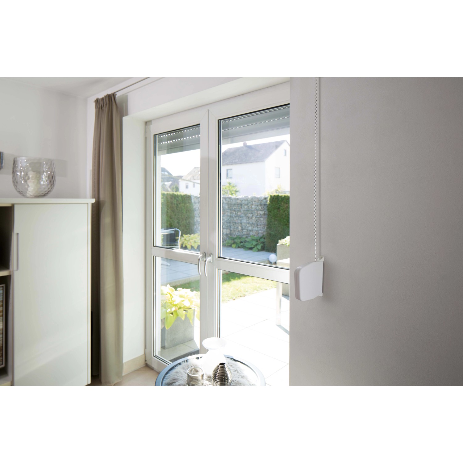 Schellenberg Rollladen-Schnurwickler mit 5 m Schnur, weiß, montiert an einer Wand neben einem Fenster.