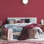 Schlafzimmer mit roter, leicht strukturierter Vliestapete Uni Matt FSC® an der Wand.