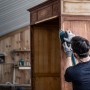 Mann schleift Holzschrank mit Bosch Expert Netzschleifblatt und Schwingschleifer.