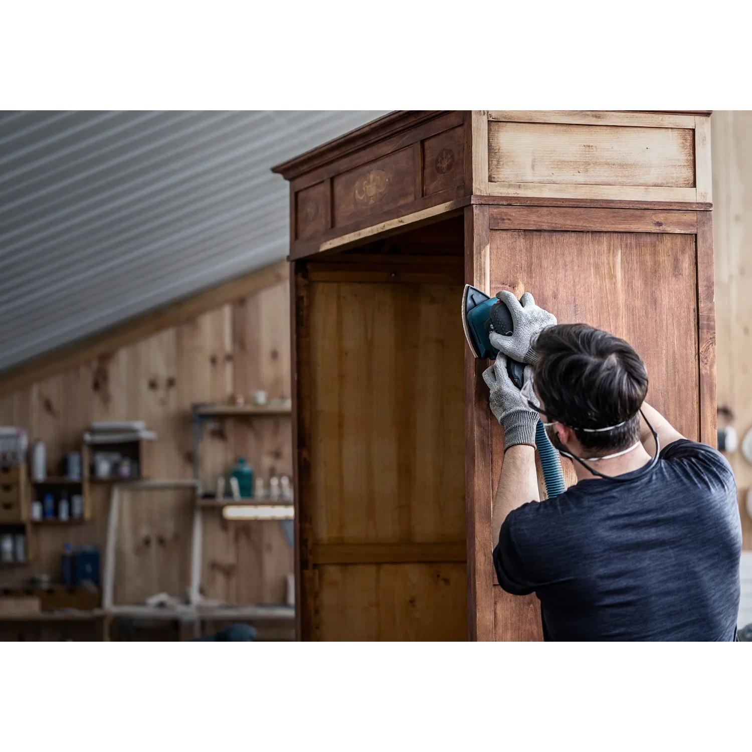 Mann schleift Holzschrank mit Bosch Expert Netzschleifblatt und Schwingschleifer.