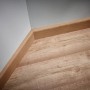 Sockelleiste aus Holz an Wand und Laminatboden, verlegt mit wolfcraft Montage-Set.