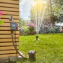 Gardena Bewässerungscomputer Select am Wasserhahn mit Rasensprenger im Garten.