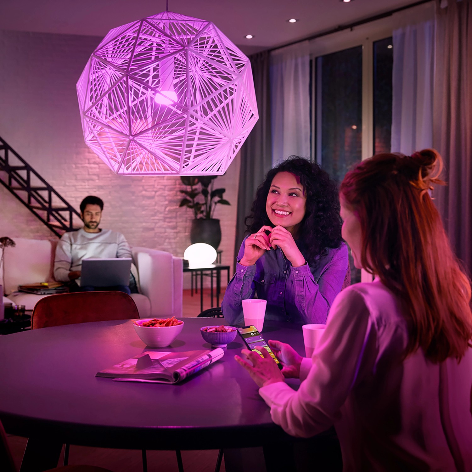 Philips Hue E27 Lampe, White & Color Ambiance, in Nutzung mit farbigem Licht über Esstisch.