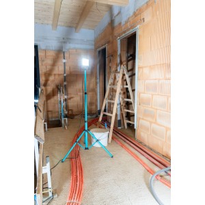 Eglo LED-Baustrahler Avelar, schwarz-türkis, mit Stativ auf einer Baustelle.