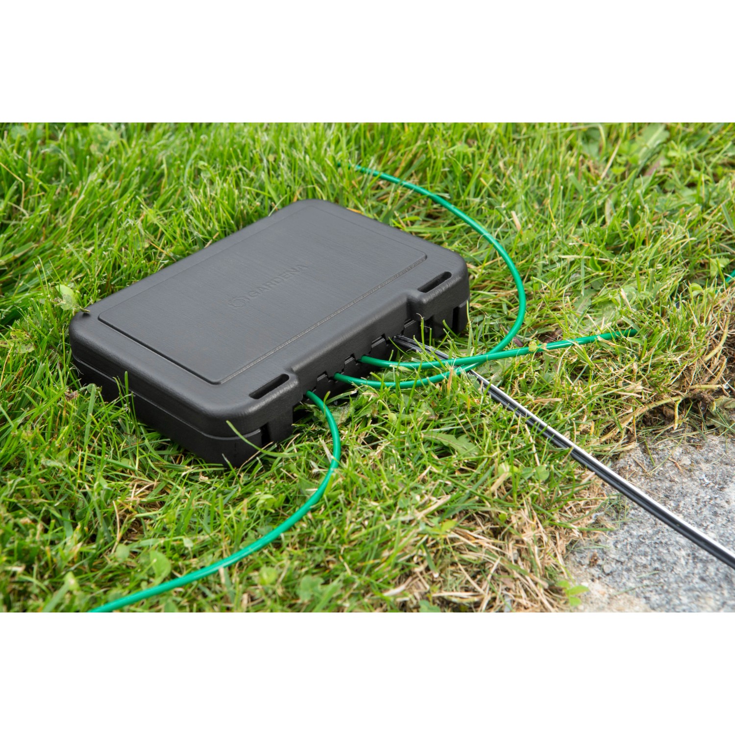 Gardena Kabelverbinder-Schutz für Mähroboter auf Rasen mit Kabeln.