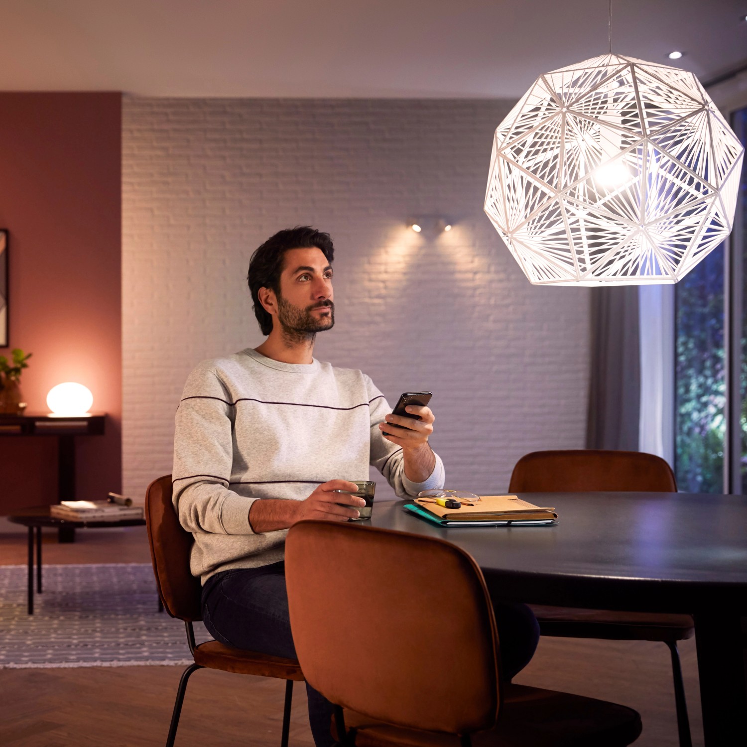 Mann steuert Philips Hue Lampe E27 mit Dimmschalter und Bridge in Wohnraum.
