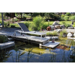 Anthrazitfarbene Acamp Sonnenliege Rimini mit Rollen auf Holzsteg am Gartenteich.