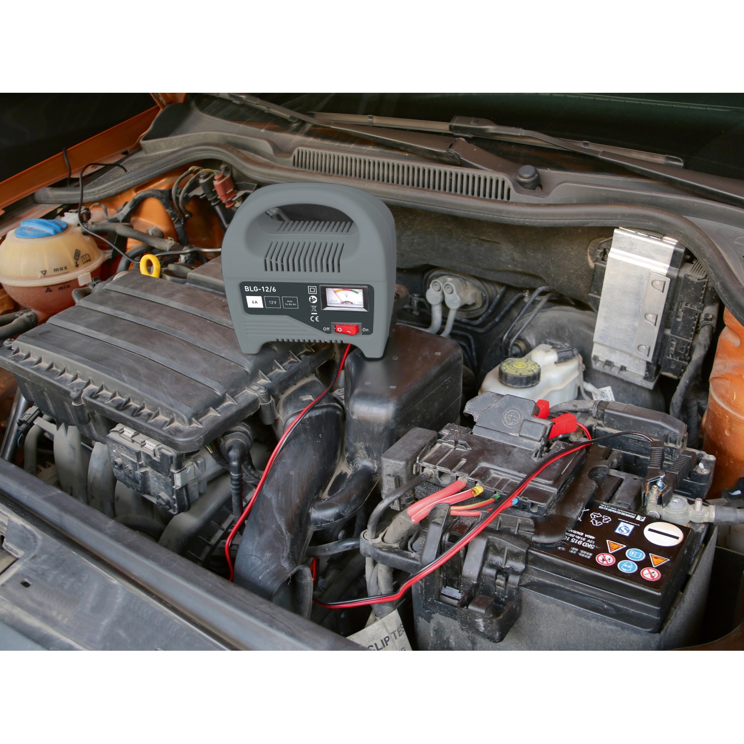 Batterie-Ladegerät 6 A im Motorraum beim Aufladen einer Autobatterie.