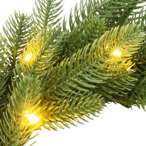Nahaufnahme grüner OBI Kunsttannen Kranz Dalbyn mit warm leuchtenden LEDs.