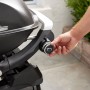 Detailaufnahme: Weber Gasgrill Q2200N mit Stand, schwarzer Grill mit Hand am Bedienknopf.