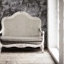 Grau-schwarze Vliestapete mit Dschungel- und Palmenmuster hinter antikem Sofa.