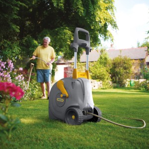 Hozelock Schlauchwagen Fast Cart mit 40m Schlauch im Garten, mit Person beim Bewässern.