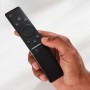 Schwarze Fernbedienung in Hand, Bedienelemente für TV und Smart-Home.
