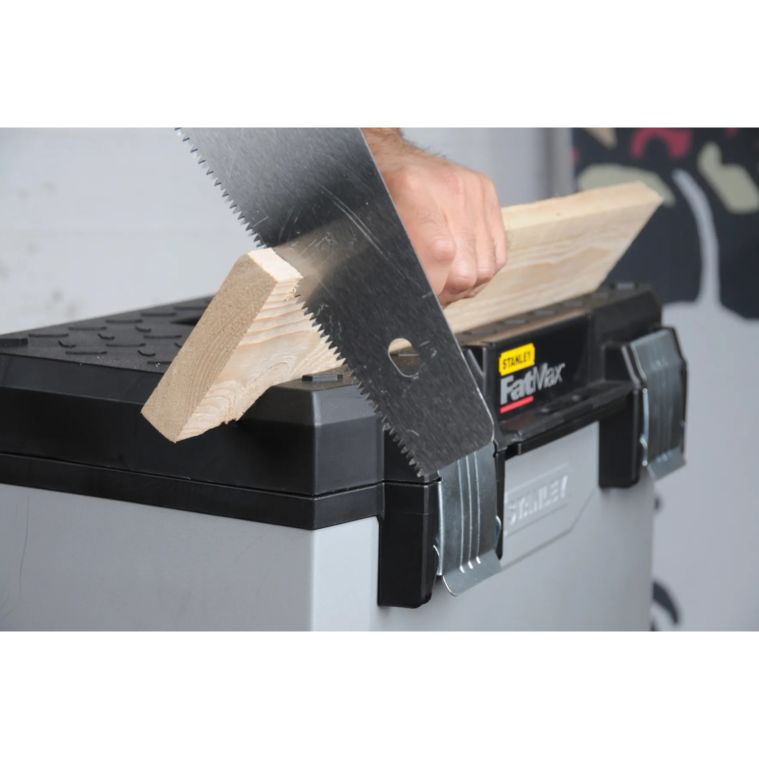 Stanley FatMax Werkstattwagen beim Sägen eines Holzstücks. Mobiler Werkzeugwagen für Handwerker.
