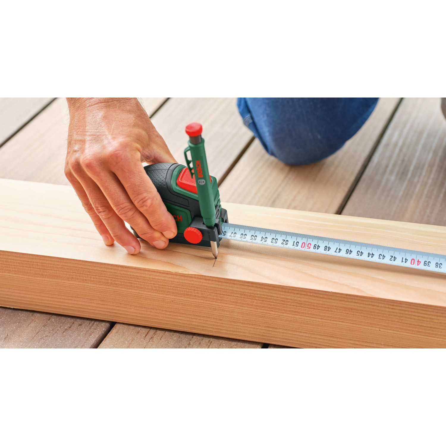 Bosch Maßband mit Tieflochmarker beim Anzeichnen eines Holzbretts. Teil des Werkzeugkoffers.
