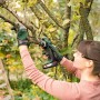 Frau sägt mit Bosch Akku-Säge AdvancedCut 18 einen Ast im Garten. Inkl. Akku.
