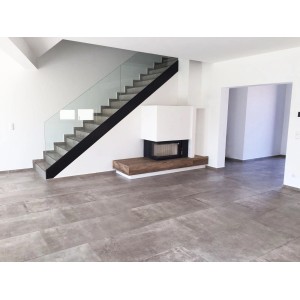 Verlegtes, graues Feinsteinzeug 60x120 cm im Wohnraum mit Treppe und Kamin.