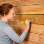 Frau trägt Xyladecor Holzschutz-Lasur Ebenholz mit Pinsel auf Holzfassade auf.