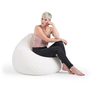 Frau sitzt entspannt im weißen Sitting Point Sitzsack BeanBag Fluffy mit Herzmuster.