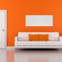 Weißes Infrarot-Heizpaneel HVH 900L Victory an orangefarbener Wand über Sofa.