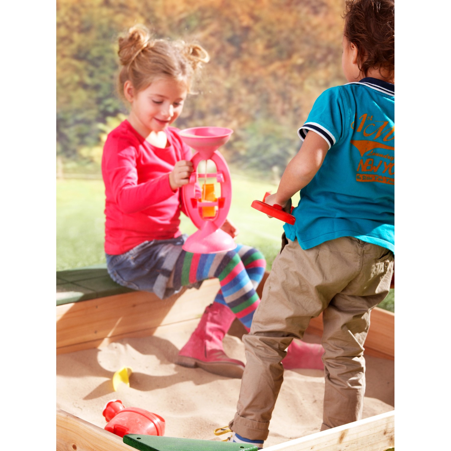 Kinder spielen im Axi Sandkasten Amy 115x115 cm mit Stauraum aus FSC®-Holz.