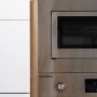 Detailaufnahme: Respekta Küchenzeile mit Einbaumikrowelle und Backofen in Edelstahloptik, weiße Fronten, Eiche Sägerau Dekor.