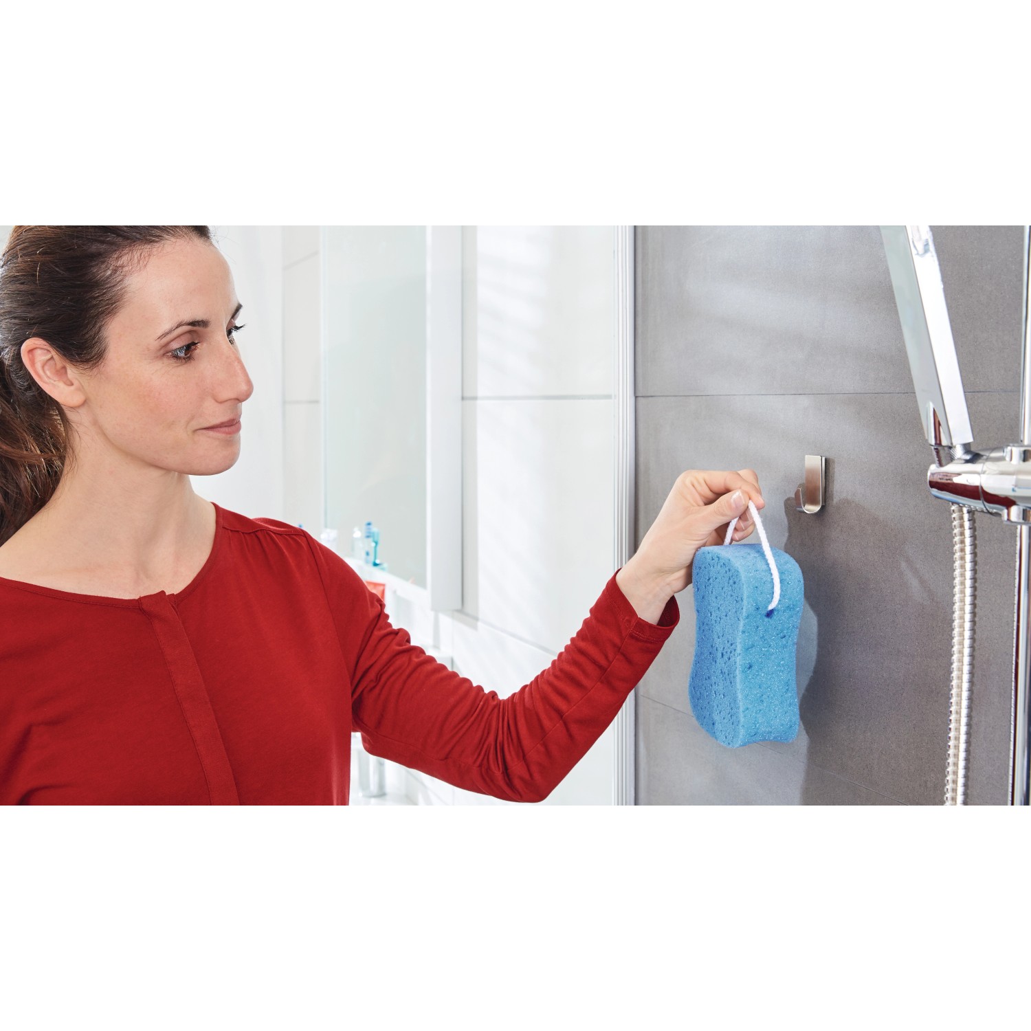 Frau hängt Badeschwamm an Tesa Powerstrips Haken Waterproof Edelstahl im Bad.