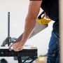 Stanley FatMax Werkbank klappbar im Einsatz: Handwerker sägt Holz auf der Werkbank.
