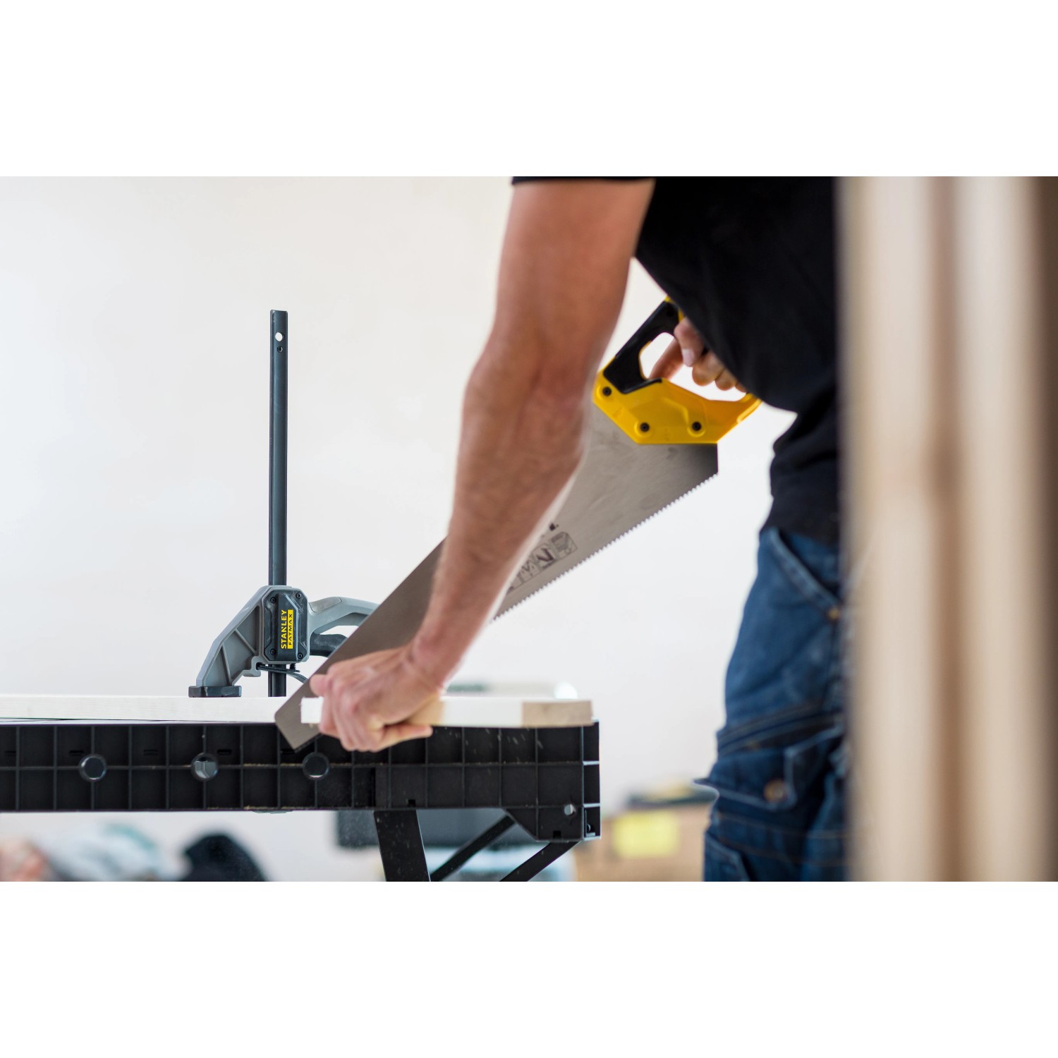 Stanley FatMax Werkbank klappbar im Einsatz: Handwerker sägt Holz auf der Werkbank.
