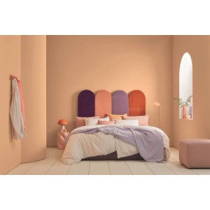 Schlafzimmer mit Wänden in Alpina Innenfarbe Pantone Peach Fuzz Pastellorange. Bett, farbiges Kopfteil, matte Wandfarbe.