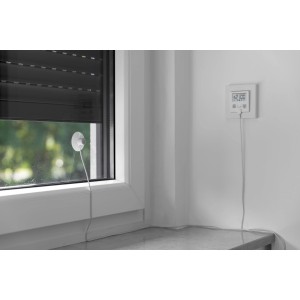 Schellenberg Rollladen Zeitschaltuhr Plus mit Sensor am Fenster und Rollladen im Hintergrund.