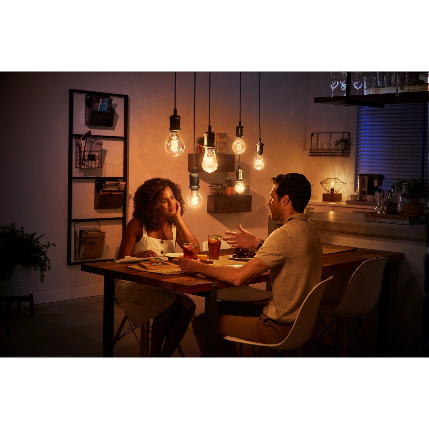 Szene mit Philips Hue Filament ST19 E27 LED-Lampen über Esstisch mit Paar.