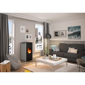 Justus Pelletofen Sirkos 2.0, 6 kW, Stahl Taupe, in modernem Wohnzimmer mit Sofa und Fenster.