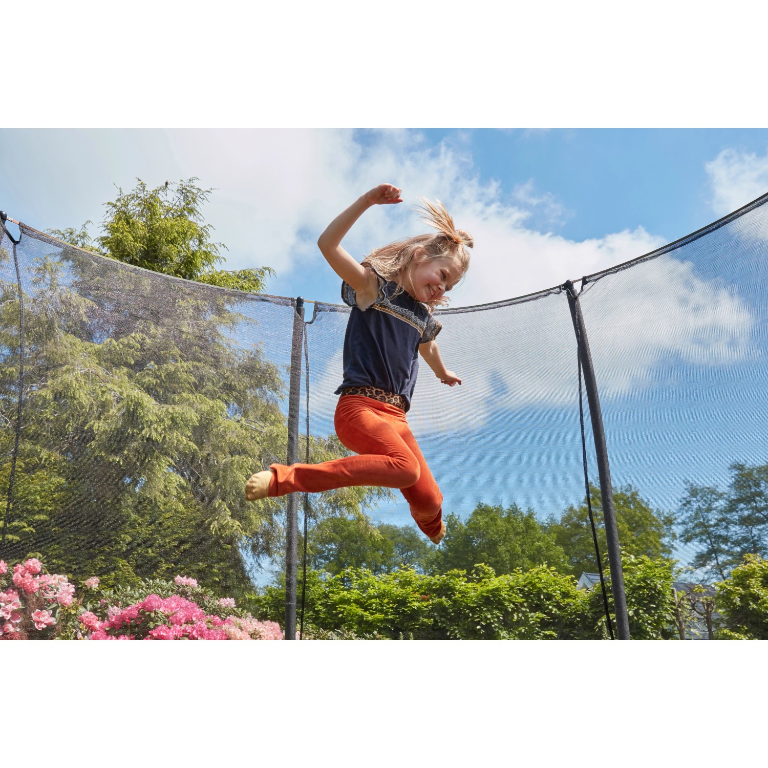 Mädchen springt auf grünem Salta Comfort Edition Bodentrampolin ø 396 cm mit Sicherheitsnetz.