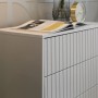 Weiße Selsey Bello Kommode mit drei Schubladen und elegantem Lamellendekor. Die matte Oberfläche ist mit Dekoartikeln geschmückt.