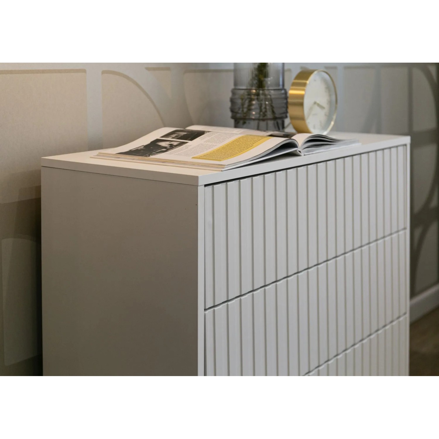Weiße Selsey Bello Kommode mit drei Schubladen und elegantem Lamellendekor. Die matte Oberfläche ist mit Dekoartikeln geschmückt.