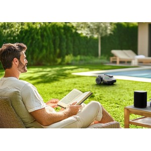 Mann liest, während Mammotion Yuka Mini Mähroboter den Rasen mäht.