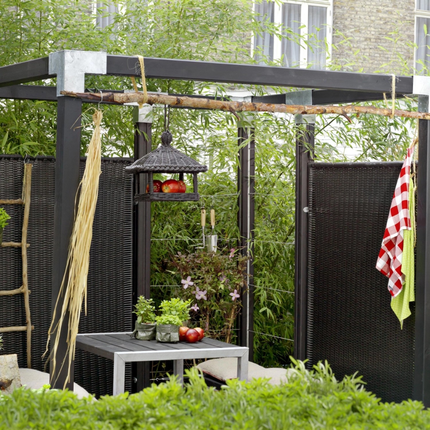 Schwarzer Polyrattan Sichtschutzzaun Trend, 115x170 cm, im Garten mit Tisch und Dekoration.