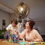 Philips LED E27 Lampe in Glühlampenform, ultraeffizient, klar, im Einsatz über einem Tisch mit bastelnden Personen.
