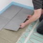 Verlegen einer Perobe Elektro-Fußbodenheizung (7,5 m²) unter grauen Fliesen.