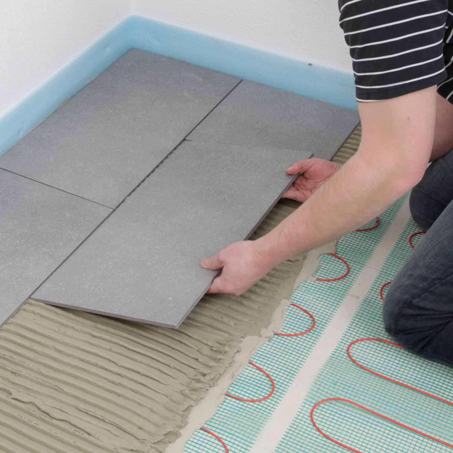Verlegen einer Perobe Elektro-Fußbodenheizung (7,5 m²) unter grauen Fliesen.