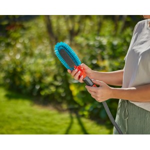 Frau hält Gardena Cleansystem Fahrradbürste mit Wasseranschluss und blauen Borsten.