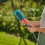 Frau hält Gardena Cleansystem Fahrradbürste mit Wasseranschluss und blauen Borsten.