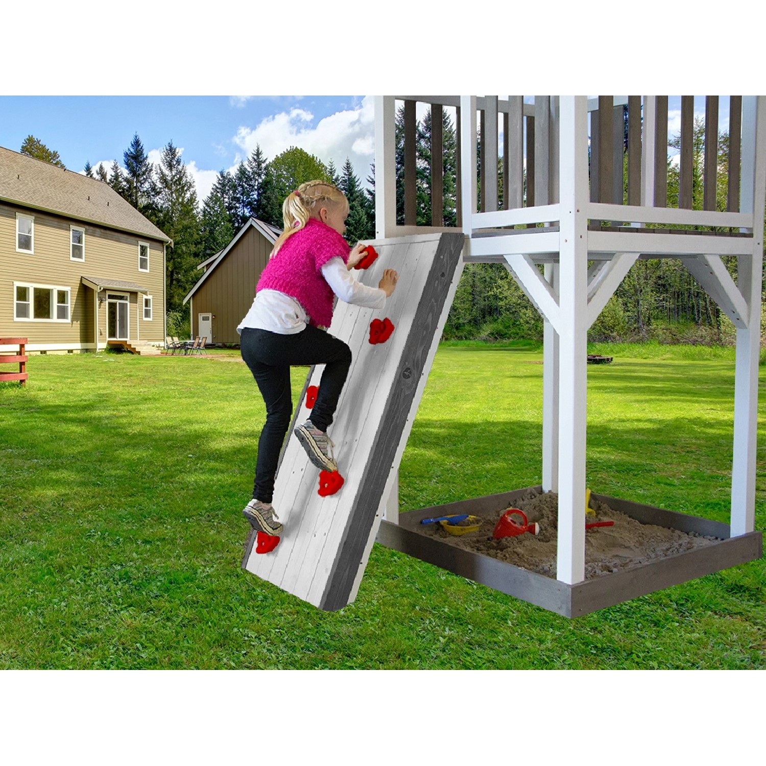 Kind klettert an der weißen Sunny Spielhaus Kletterwand mit roten Griffen im Garten.
