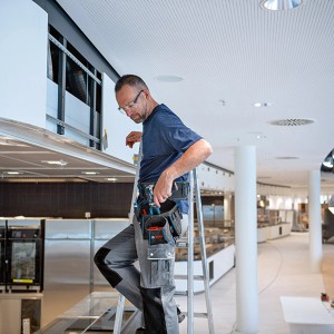 Handwerker mit Bosch Werkzeuggürtel und Werkzeugtaschen auf einer Leiter.
