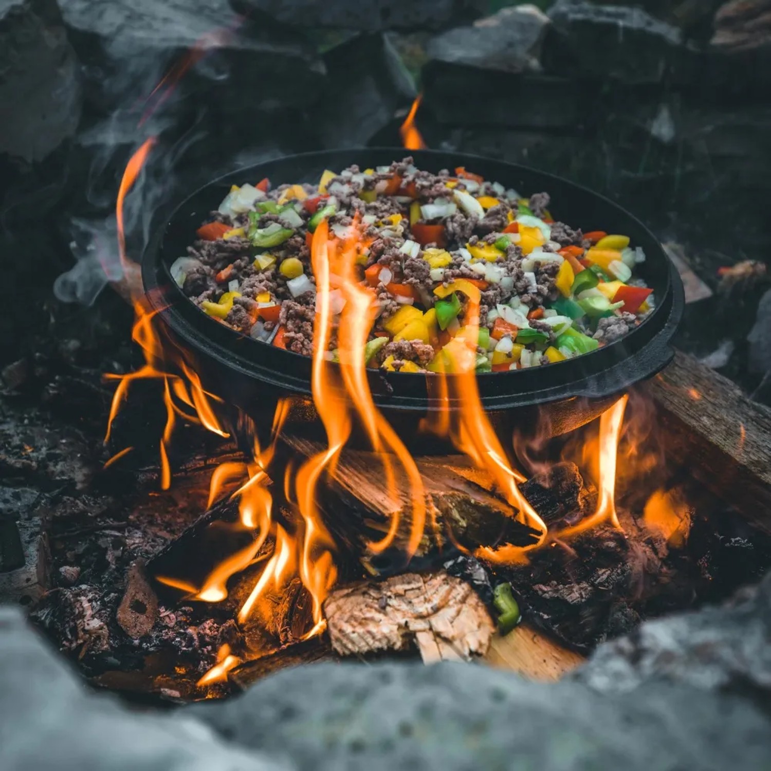 Petromax Dutch Oven FT9 auf offenem Feuer mit Gemüse und Fleisch. Gusseisen Topf für Outdoor-Küche.