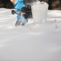Person schaufelt Schnee mit der Fiskars Schneeschaufel Telescopic X-series.