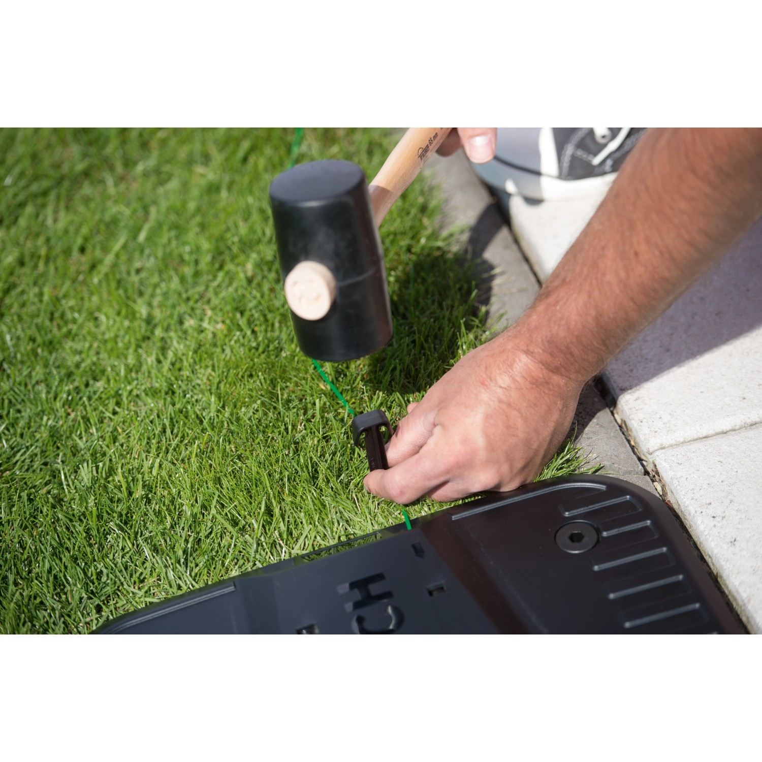 Bosch Fixierstifte Indego beim Fixieren des Begrenzungsdrahts im Rasen.