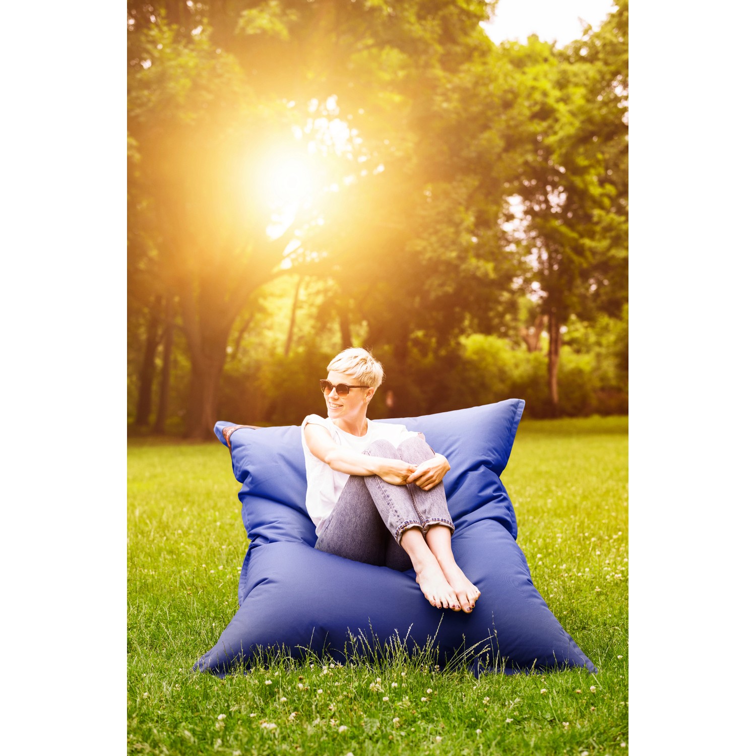 Frau entspannt auf pinkem Sitting Point Sitzsack Big Foot Scuba (380 l) im Garten.