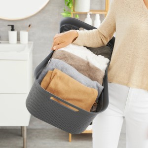 Anthrazitfarbener Rotho Wäschekorb Brisen (41 l) mit Wäsche in der Hand einer Person.